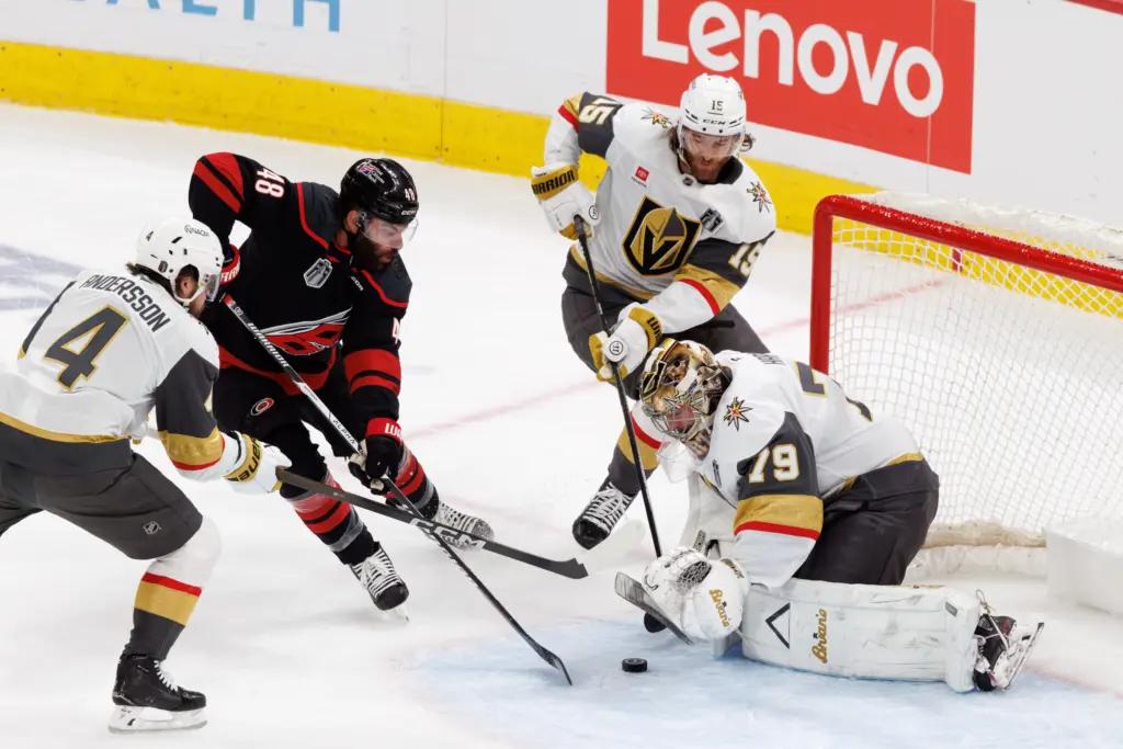 Carolina Hurricanes' Jordan Martinook (48) reaches for a puck near the goal between Vegas Golden Knights' Rasmus Andersson (4), Noah Hanifin (15), and Vegas goaltender Carter Hart (79) during the first period of Game 2 of the NHL hockey Stanley Cup Final series in Raleigh, N.C., Thursday, June 4, 2026. (AP Photo/Ben McKeown)