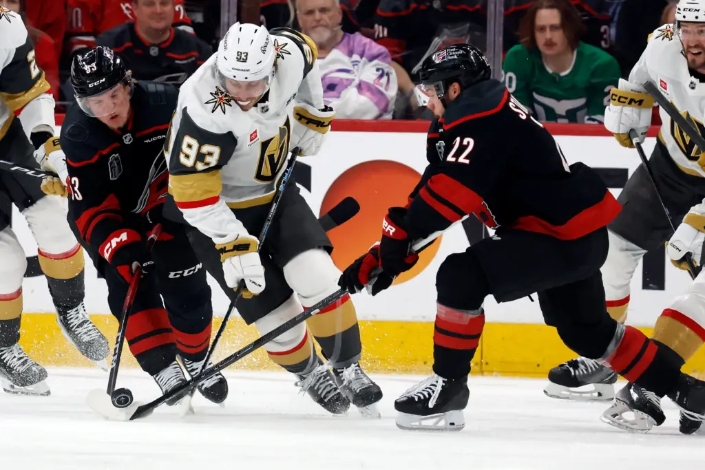 Vegas Golden Knights' Mitch Marner (93) tries to control the puck as his skates between Carolina Hurricanes' Logan Stankoven (22) and Jackson Blake (53) during the first period in Game 2 of the NHL hockey Stanley Cup Final series in Raleigh, N.C., Thursday, June 4, 2026. (AP Photo/Karl DeBlaker)