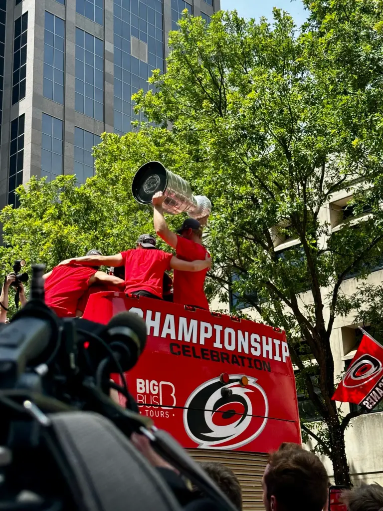 Members of the Carolina Hurricanes hold up the Stanley Cup while riding through the streets of Raleigh during the victory parade. (Russ Bowen)