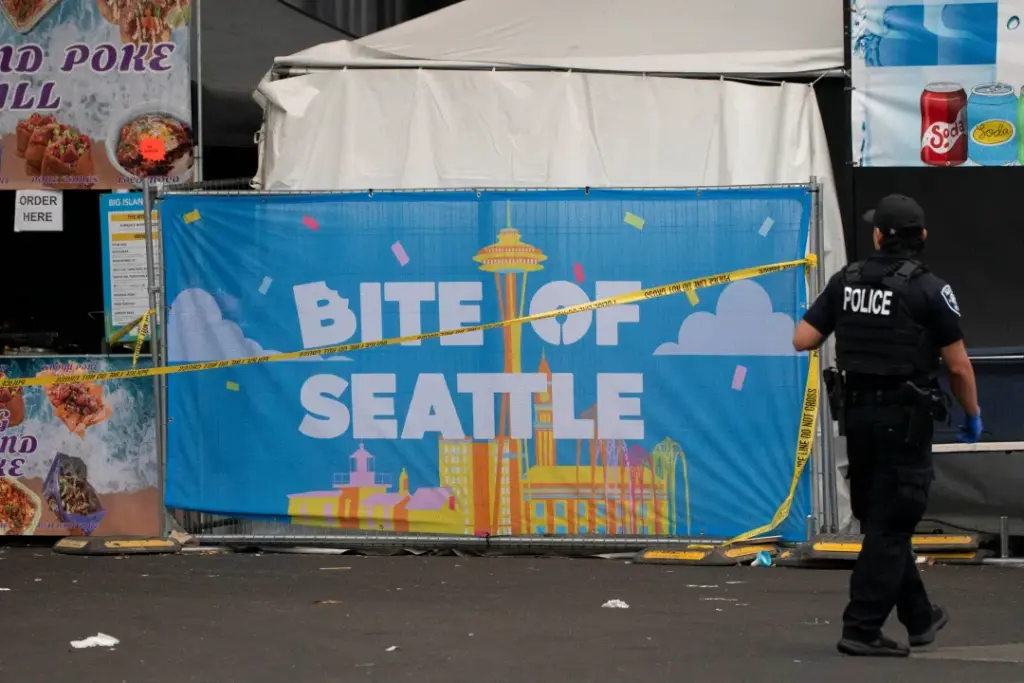 A police officer walks by a sign for the Bite of Seattle food festival