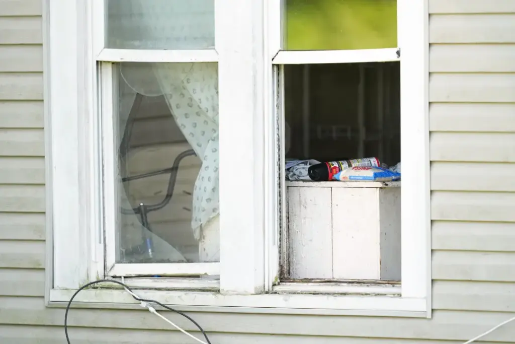 A bag of rice and a can of insect killer sit in an open window of a home